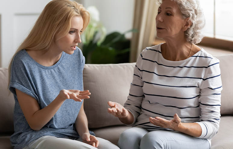 Stressed young blonde grown up daughter arguing with nervous old mature mother, sitting together at home. Irritated elderly woman lecturing adult child, different generations misunderstanding gap.
