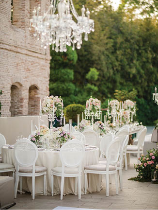 White color wedding table decorated with decorative and elegant for wedding. There are flowers, candles and serving plates on the wedding table.