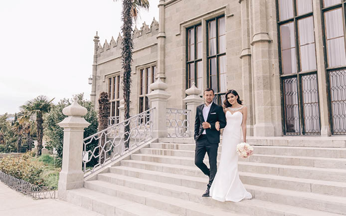 love story. wedding photo of beautiful tender couple. gorgeous woman in luxurious wedding dress and her handsome husband posing near antic castle