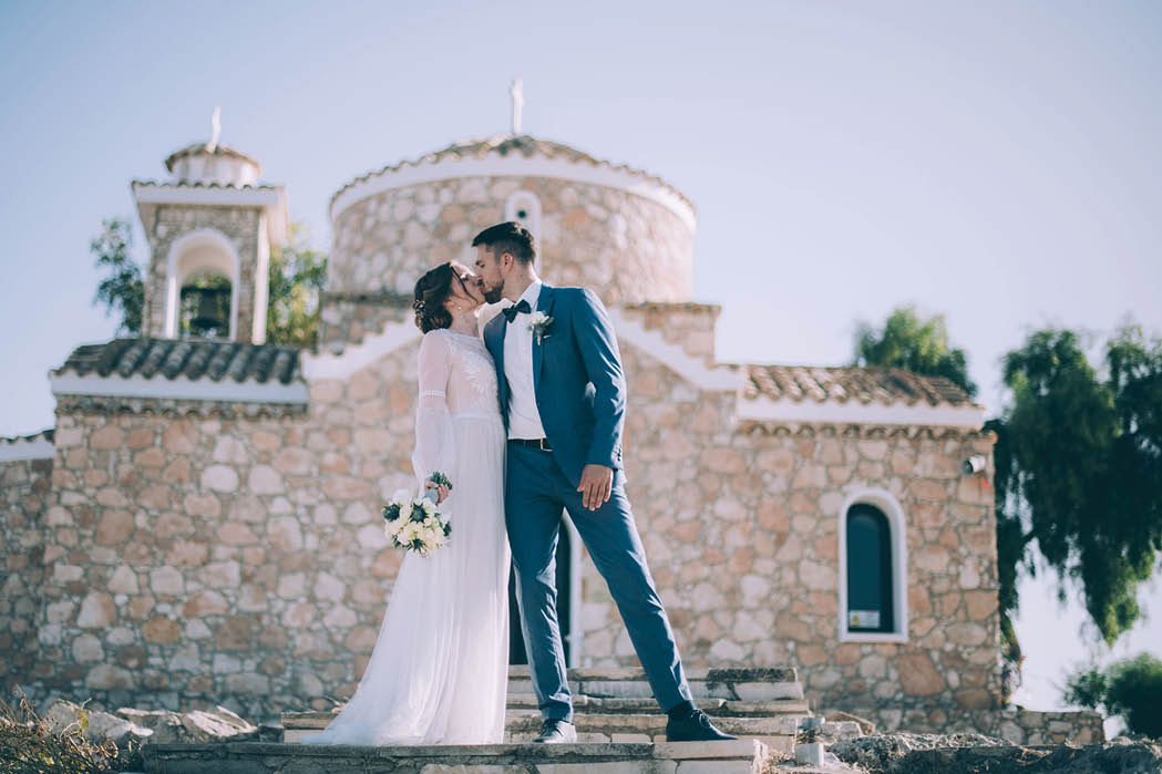 Wedding in Cyprus. A couple of newlyweds are photographed near the walls of the Temple of Elijah the Prophet in Protaras. A man and a woman in love in wedding clothes at a photo shoot in Cyprus