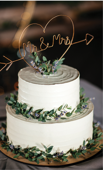 Beautiful small wedding cake decorated with a greenery, outdoors 