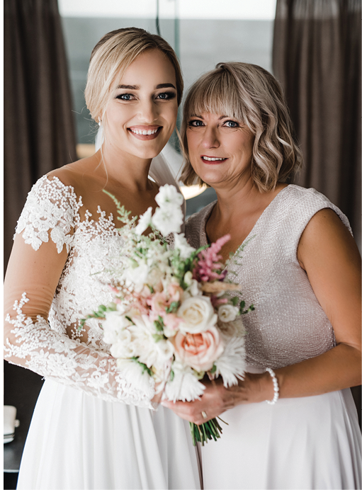Latvia, Riga - August, 2020: Wedding photo session - smiling white Caucasian Bride with blond hair, flowers and mother are posing indoors at wedding day 