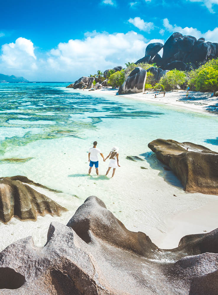 A young couple standing in shallow water on La Digue island, Seychelles
