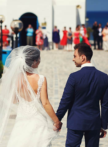 Young beautiful stylish couple newlyweds outside the church on the day of their wedding on the island of Santorini, Greece 