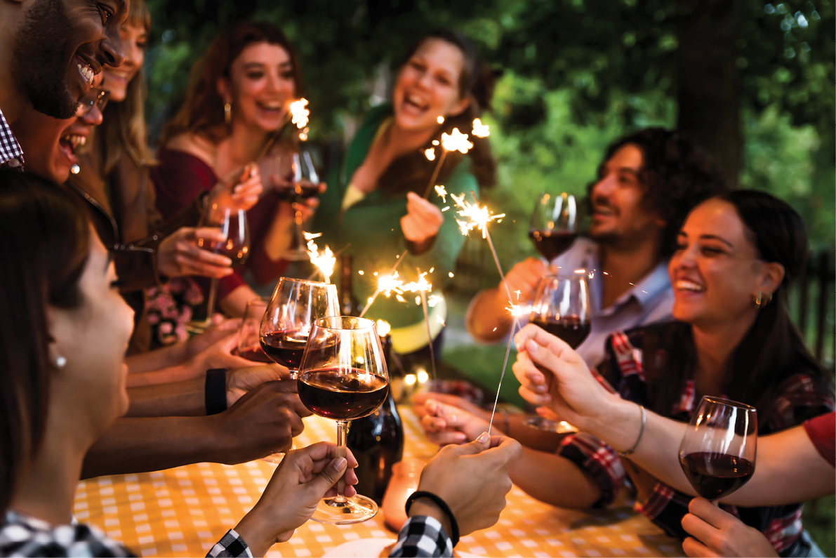 Happy family celebrating with fireworks at barbecue backyard party - Young people having fun with fire sparklers at night time - Friends drinking red wine at farmhouse restaurant - Youth concept