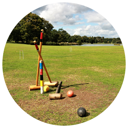 Field trees and cloudy blue sky featuring a croquet set and balls unattended as if left behind after a game