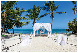 Colorful wedding arch gazebo pavilion made of bamboo and textile with fresh flowers decoration at sandy beach on sunny day for destination wedding ceremony in Dominican republic 