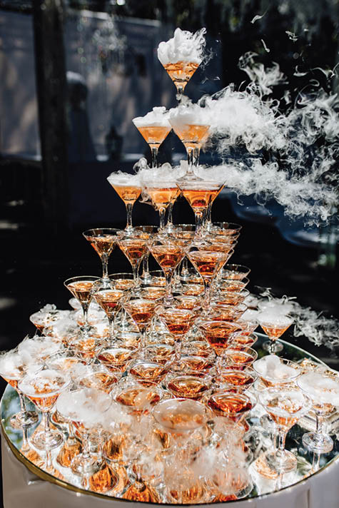 Beautiful Smoking Glasses with Champagne Tower. Bright Elegant Restaurant Decoration with Amazing Special Effect Standing on Mirror Table. Luxury Detail with Alcoholic Drinks for Guests