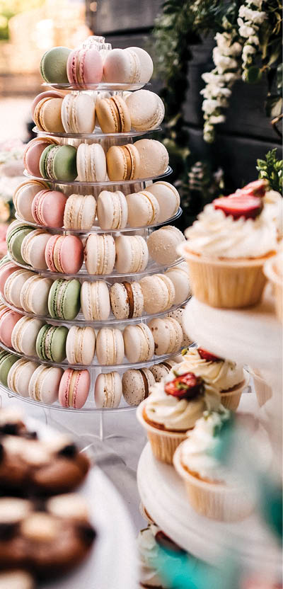 Candy-bar at a wedding with a lot of sweets in pastel colors, macaroons, biscuits, cupcakes with whipped cream, berries.
