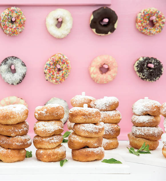 Freshly baked doughnuts in composition on pink wall. 