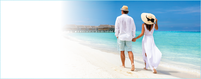 Happy couple in white clothing and with hats walks down a tropical beach with turquoise sea in the Maldives islands