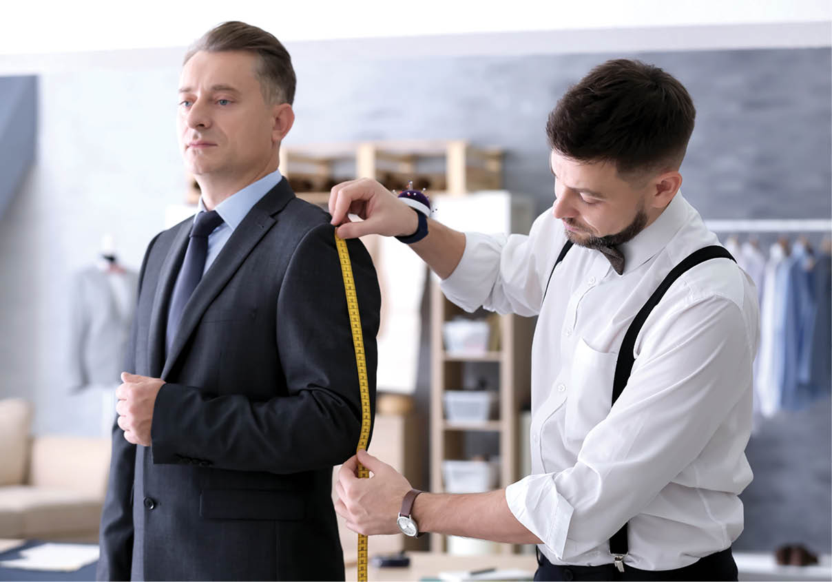 Tailor taking man's measurements in atelier