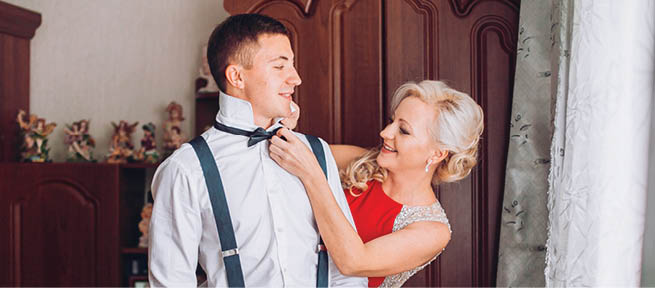 Mother is helping with a bow-tie to her son before wedding ceremony 