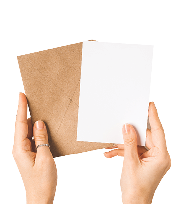 Craft paper envelope with white blank paper note mockup in woman hands, with cup of coffee, gold binder clips and flowers on white background  Flat lay, top view  Invitation, package and letter 