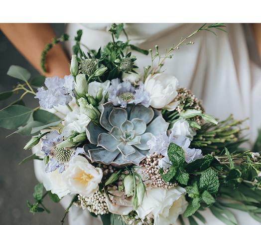Bridal bouquet. Wedding. The girl in a white dress sitting on a wooden chair and holding a beautiful bouquet of white, blue, pink flowers and greenery, decorated with silk ribbon