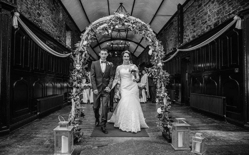 bride and groom under flower arch